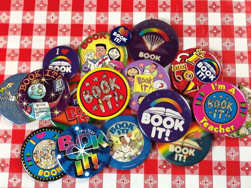 Pins advertising the "Book It" program arranged on a Pizza Hut tablecloth